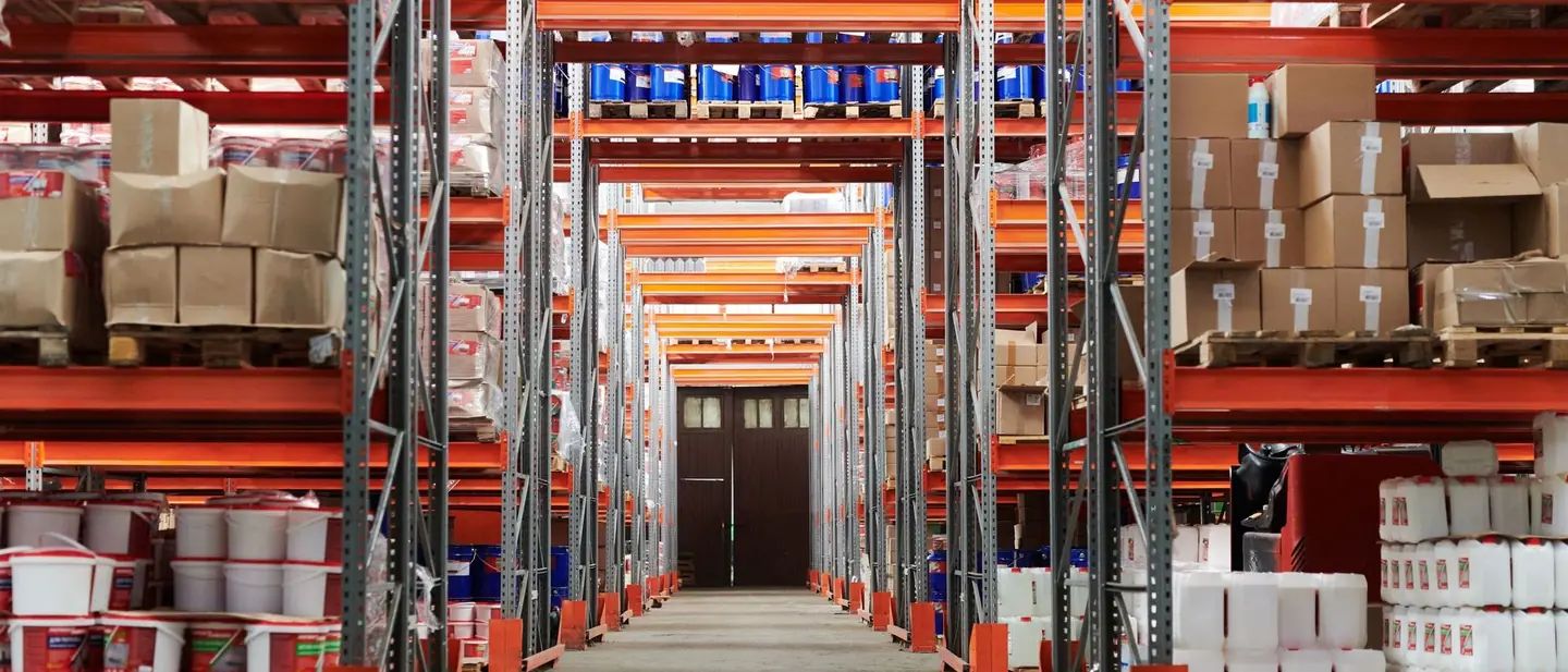Warehouse aisle between tall racks of boxed and palletised stock